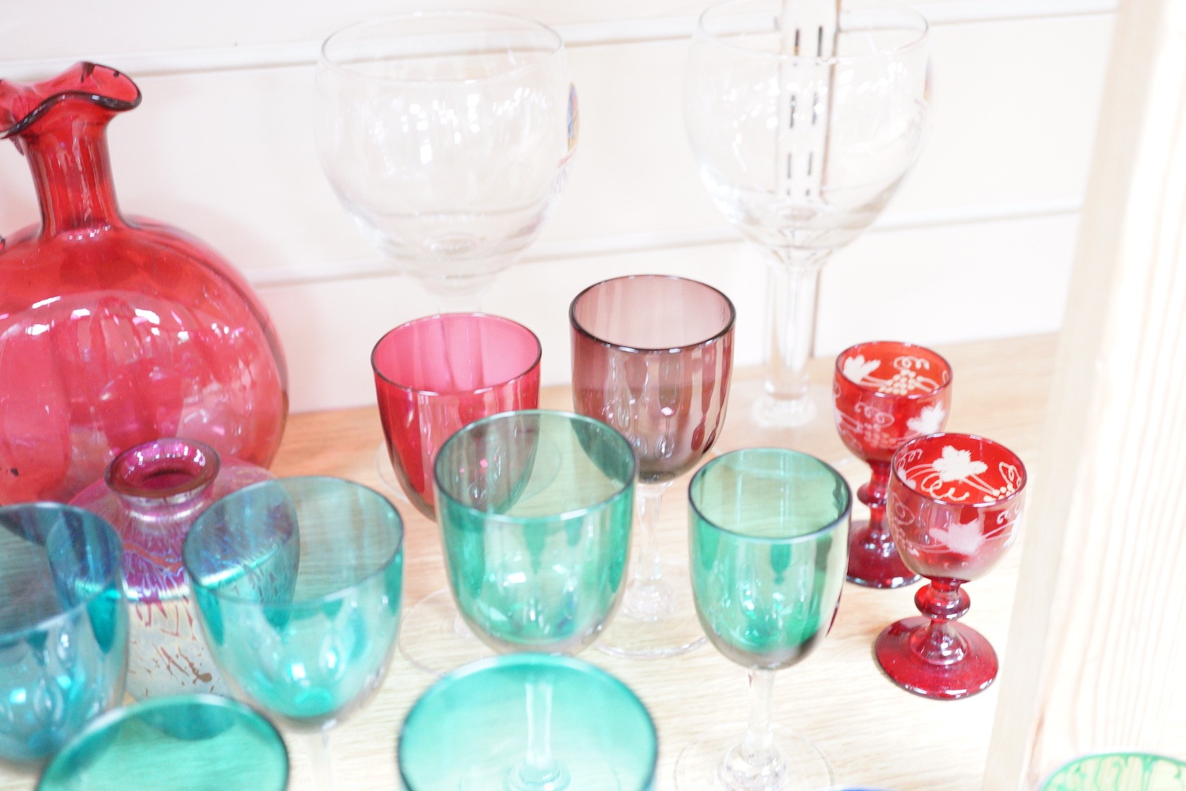 A quantity of cranberry glass, together with other coloured glassware and a Murano style fish ornament